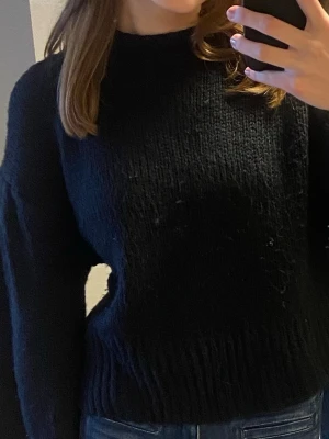 Svart stickad tröja med hög hals - Mysig svart stickad tröja med hög hals och långa ärmar. Storlek S