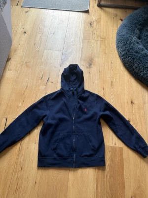Mörkblå hoodie från Polo Ralph Lauren - Hej, säljer en snygg mörkblå hoodie från Polo Ralph Lauren med dragskedja. Tröjan är i riktigt bra skick och använd fåtal gånger. Passformen är bra och perfekt och stilren look😍          Priset kan diskuteras vid intresse👍🏼