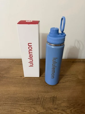 Blå vattenflaska från Lululemon - Snygg blå vattenflaska från Lululemon i rostfritt stål med praktiskt skruvlock och bärhandtag. 710ml