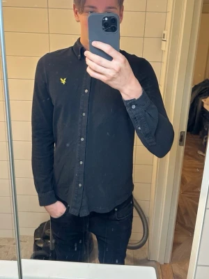 Svart skjorta  - Super snygg Lyle & Scott skjorta i färgen svart. Använd fåtal gånger, säljer då den inte används! 100% Bomull.