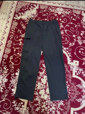 Svarta Johan Skoglund Cargobyxor - Säljer ett par svarta cargobyxor med klassisk rak passform och en stor ficka på benet. Byxorna har dragkedjegylf och knapp i midjan samt hällor för skärp. 2 för 120 kr på alla herrbyxor. 