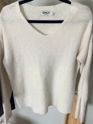 Vit stickad tröja från ONLY - Klassisk vit stickad tröja från ONLY med v-ringning och långa ärmar. Tröjan har en enkel, ribbad struktur och är perfekt för lager på lager. Mjuk och bekväm, passar till många olika stilar.