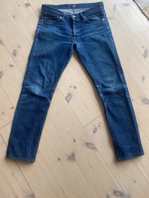 Mörkblå slim jeans från APC - Snygga mörkblå jeans från APC med smal passform och klassisk femficksdesign. Jeansen har subtila slitningar och är tillverkade i selvedge tyg som  Perfekta för dig som gillar stilrena och tidlösa jeans.