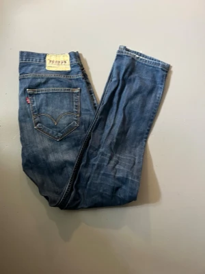 Blå Levi's jeans 504 - Säljer ett par blå jeans från Levi's med klassisk femficksdesign och ikonisk läderpatch bak i midjan. Jeansen har raka ben och tydliga kontrastsömmar. Perfekta för dig som gillar tidlös denimstil.