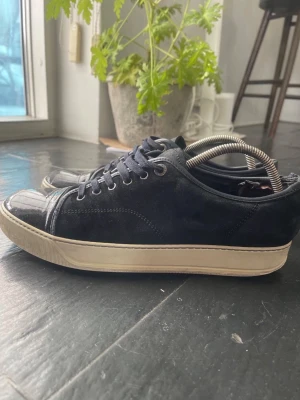 Svarta sneakers med mockadetaljer -  Svarta lanvins med glans. Skorna är i mocka men kommer utan og saker. Är hyfsats bra skick och har en slitning i skon😁