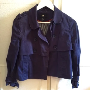  - Säljer en fin mörkblå kort trenchcoat från H&M! Jackan har randigt foder inuti! 
