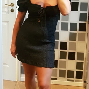 Stretchig klänning med puffärm - Fin klänning i stretchigt material med knytning, puffärm och En liten volang nedtill.