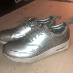 Silvriga nike skor - Nike sneakers i modellen Air Max Thea i silver strl 39. Flitigt använda därav det låga priset. Väldigt bekväma och snygga! 