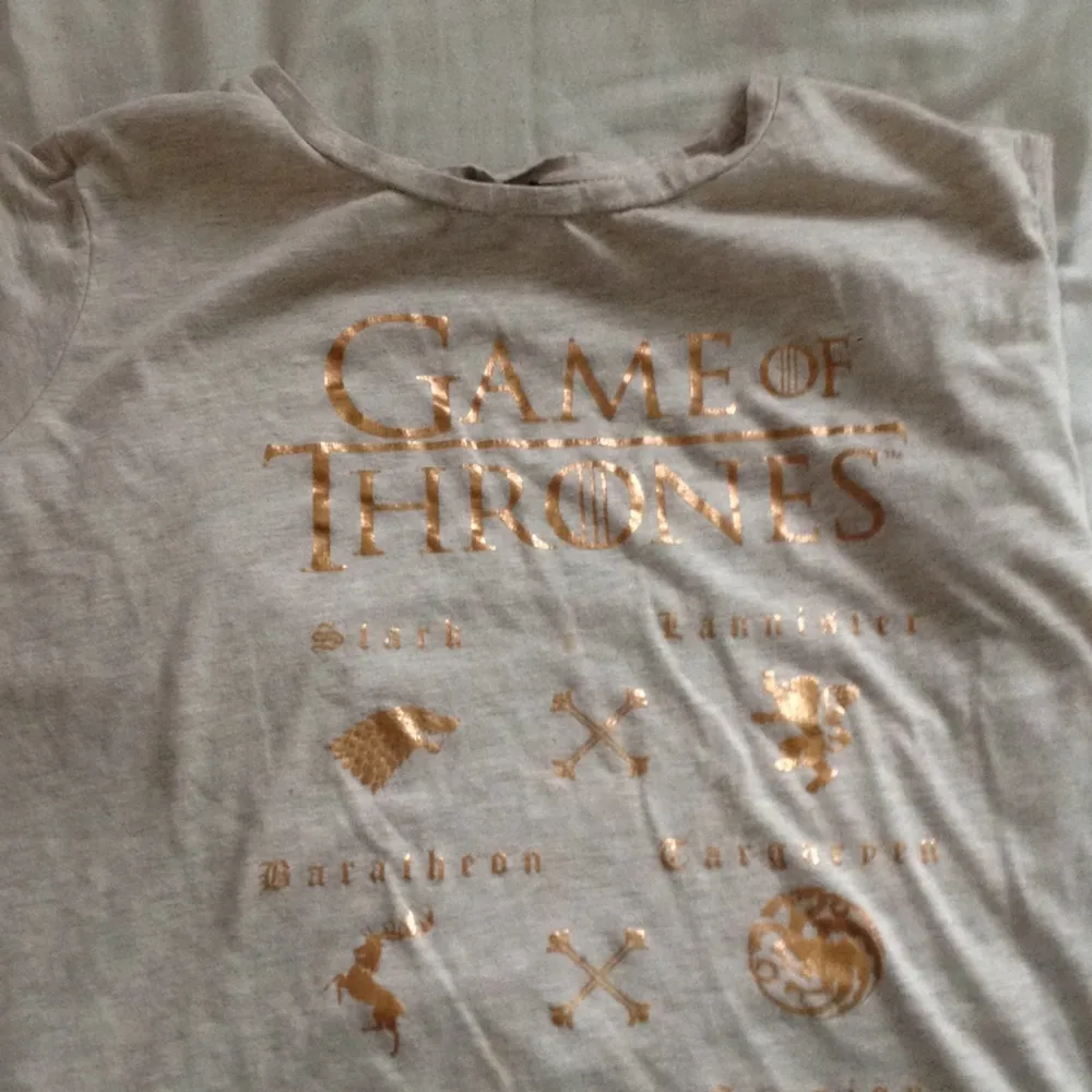 Vilken klan tillhör du? Stark eller Lannister?  En GoT tröja med tryck i ett bronze färg! Perfekt för GoT nörden!. T-shirts.