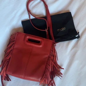 Maje Väska - Maje mini Väska i röd färg. Köpt för 1800kr. Tillkommer en dustbag. Antigen crossbody eller hålla i handen.