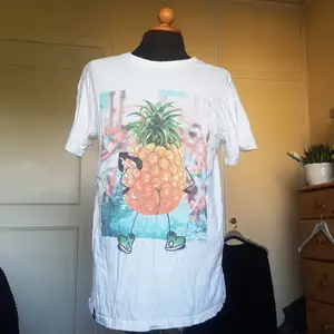 Denna t-shirt med ett tryck av en ananas med glasögon, skor och en bar rumpa säljes då den blev använd en gång och sedan dess legat i garderoben. Rätt oversize men rolig. Från tshirtstore. Passar alla. 