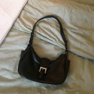  - Svart liten axelremsväska i läderimitation, oanvänd i skicket. 👜 Frakt tillkommer.