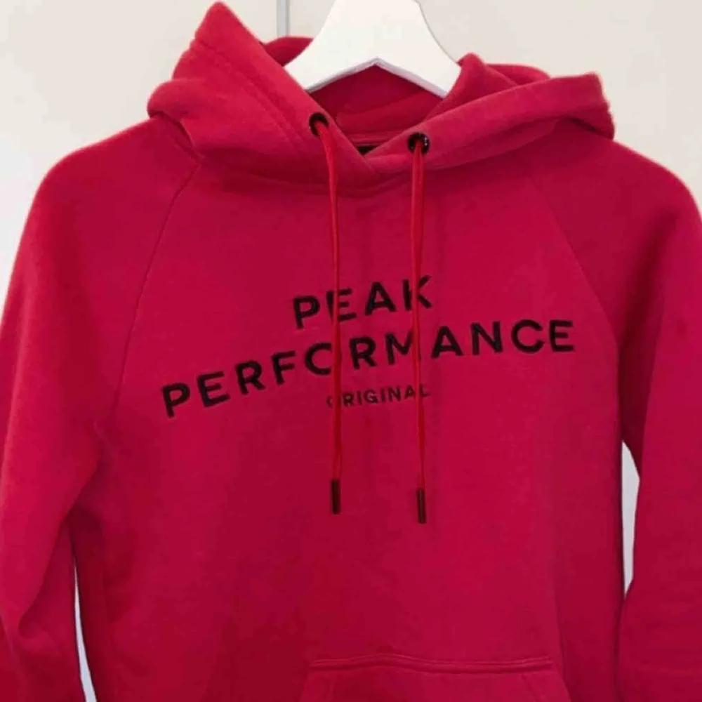 Väldigt fin hallonröd hoodie från Peak Performance med svart tryck, sparsamt använd och i väldigt bra skick. Storlek XS.. Hoodies.