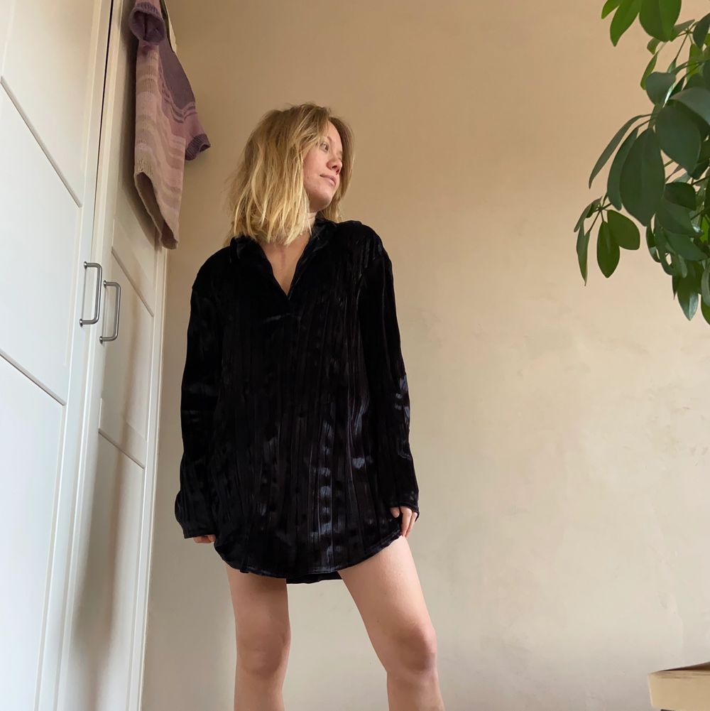 Säljer denna snygga velour-klänning i svart med djup v-ringning och krage. Den är så blank och skiner så den upplevs glittrig. Hänger sjukt snyggt på kroppen och är i fint skick. Passar både med som utan något i midjan och har själv både använt med något under samt utan. En perfekt party-blåsa! . Klänningar.