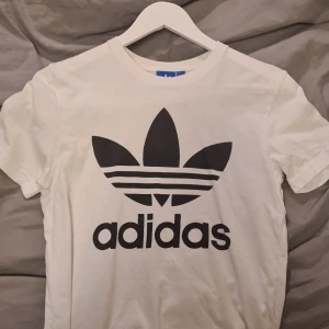 Adidas t-shirt  - Adidas t-shirten är i storlek xs och är köpt på Adidas butiken i Stockholm. Skicket är 6/10. Anledningen till att skicket är så pass öågt är för att det är ett väldigt litet hål på ena ärmen. Utöver det är skicket bra. Ny pris är 299kr, mitt pris är 70kr inklusive frakt.
