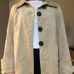 Beige manchesterjacka från Zara - Superfin beige machesterjacka från Zara med tre stora knappar framtill, detaljer baktill samt på ärmarna och ett silkesliknande foder inuti. Nyskick! Storleken ska vara XL men skulle säga att den passar från S-XL då jag kan ha den och i vanliga fall har S-M i jackor. Frakt tillkommer men kan även mötas upp i centrala Göteborg!:)                                                                                                                            (Säljer just nu massa fler kappor och jackor så kolla gärna in min profil!)