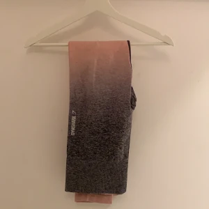 Gymshark leggings  - Nu säljer jag mina gymshark träningsbyxor I storleken M. De är en gammal kollektion från deras origanalsida, (kommer nämligen inte ihåg namnet på kollektionen). Dem är iafall gråa med en rosa fade. Jätte snygga på och seemless när de sitter på. Använda par gånger men fortafarnde bra skick och helt som nya. Skicka en dm ifall de behövs mer bilder🥰