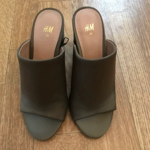 Olivgröna mules  - Storlek 36, från H&M. Aldrig använda! Finns i Eskilstuna eller så kan de fraktas som köparen står för. 