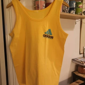 Gul Adidas topp / tank - Retro vintage  - Supercool vintage topp från adidas.  Uppskattar till en XL. Mycket stretchig.  Har en liten fläck nere vid sidan. Annars mycket fin. Funderade på att croppa den först, men den är för stor för mig, men om man vill så kan den ju även bli en cool croptop!! 