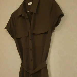 Olivgrön "Utility"-klänning - Olivgrön, viskos- och nylontygn, stl.34, 2 bröstfickor, rak i modellen, uppvikta ärmfållar, vadlång, med midjeband, knappt använd