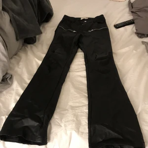 Utsvängda skinbyxor från nakd - Jätte bekväma skinbyxor som är utsvängda med silver kedja detalj vid höften.