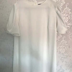 Vit sommarklänning - Vit klänning med insydd undeklänning och puffärmar med pärldetalj. Från Zara storlek L, normal passform.  Frakt tillkommer.