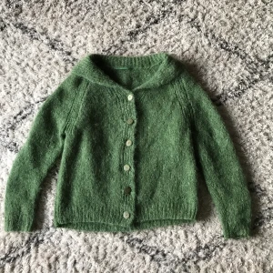 Grön stickad vintage kofta  - Stickad grön kofta köpt secondhand! Inte rekommenderbar för någon med känslig hud men med en långärmad så funkar det :) hål på framsidan se bild 2 💕 köparen står för frakt annars möts vi i Liljeholmen eller slussen ✨