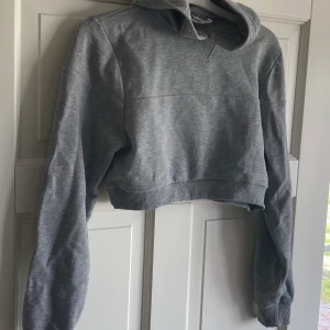 Grå hoodie från Na-kd, strl S.  - Crooped grå hoodie som är jättefin men har redan en nästan exakt likadan så säljer av min ena. Väldigt fint skick, använt några få gånger i strl S. Köparen står för frakt. 