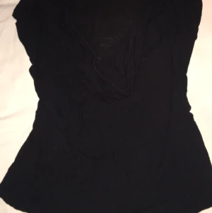 Fin svart top! - Supersnygg top! Tyvärr för stor för mig men skulle sitta perfekt på en som har storlek M! Skönt tyg och formar kroppen fint! Titta noga då det är en v-ring som är volang eller vad man kallar det, ser snyggt ut på! Bra skick! Hämtas i Skåne eller fraktas!