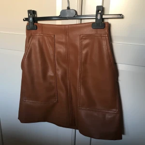 ”Skinn” kjol, brun - Jättesnygg brun ”skinn” kjol med fickor på framsidan från hm i stl 34, i nyskick. 100kr + frakt