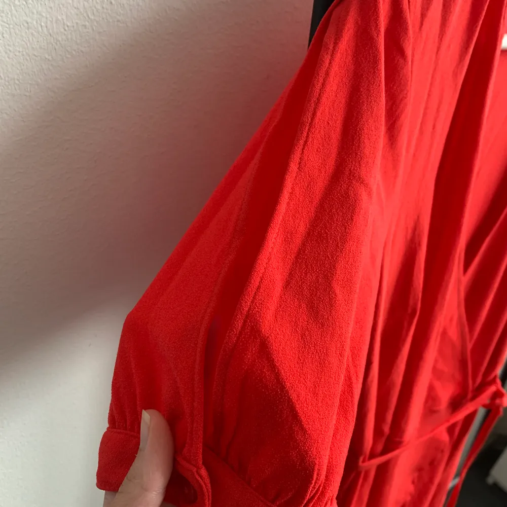 Fin omlott klänning med möjlig justering med snörena, har fin liten detalj på ärmarna med en slits. Faller fint och fin röd färg!. Klänningar.