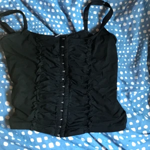 Svart korsett topp - Svart korsett topp med knäppen fram💕.                       Frakt tillkommer på 50kr!!                                    Säljer en liknande fast röd också så kolla in min profil!!