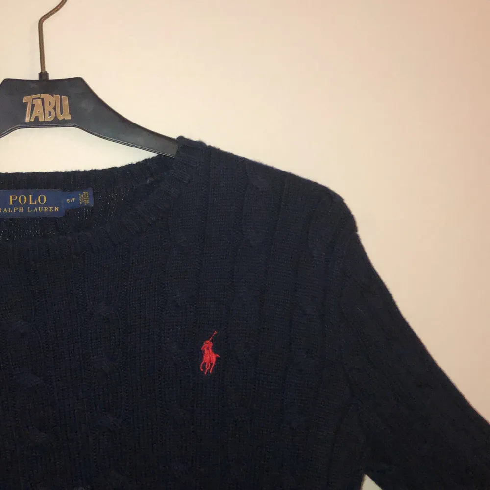 Kabelstickad tröja från Ralph Lauren i nyskick. Marinblå med röd logga. Väldigt fin men inte min stil längre. Tröjor & Koftor.