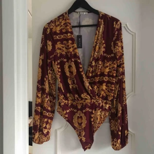  - Mönstrad body med armar. Aldrig använd, lapp finns kvar på bodyn