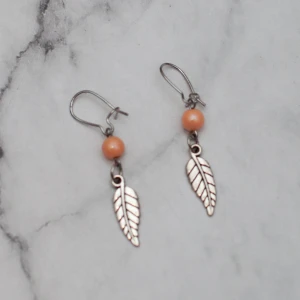  - Fina örhängen med aprikos pärla och löv. Den aprikosa pärlan är lite ljusare än på bilden. Nickelfria. Fri frakt vid köp över 100:-.