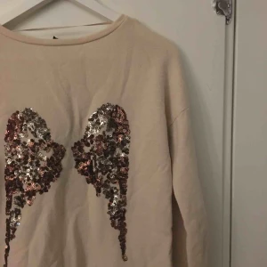  - Beige tröja men änglavingar baktill, endast använd en gång!