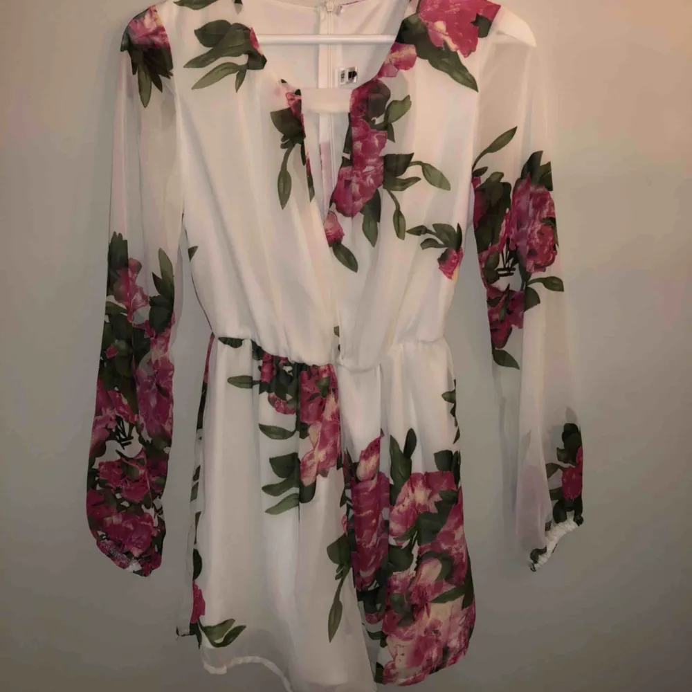 Jumpsuit/playsuit från Dennis Maglic (DM Retro), vit med rosa  blommor 💓💓 Använd 2 gånger vid avslutningar, fint skick. Storlek XS men passar mig som vanligtvis bär S 170cm lång, ganska kort men visar inte rumpis 🤪. Klänningar.