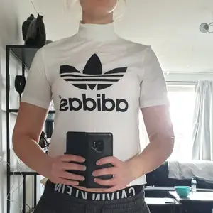En Adidas polo t-shirt med dragkedja i halsen. Begagnat skick. Frakt tillkommer