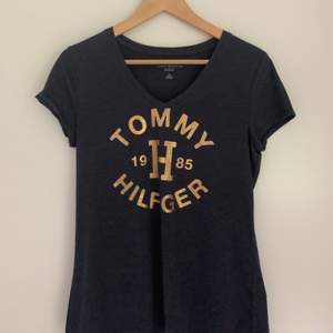 Marinblå t-shirt med guldglittrigt tryck från Tommy Hilfiger i nyskick. Classic fit i storlek S! 150kr + frakt 🪐
