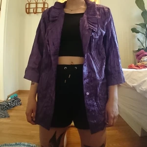 Retro lila skjorta - Retro lila skjorta med krås och axelvaddar. I gott skick. Jag på bilden är 165 lång och har vanligen storlek s/m
