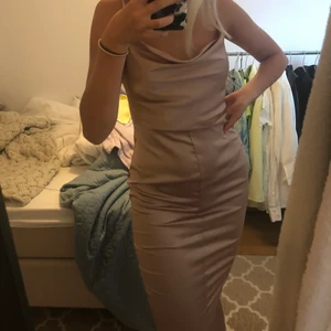 Rosa Satinklänning med snörning i ryggen - Strl 36, aldrig använd. Sitter fint på kroppen och bra material. Frakt tillkommer