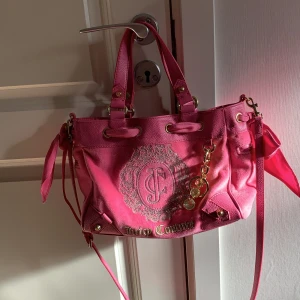 Äkta Juicy Couture väska - Väska från Juicy Couture i sammet och fake skinn med gulddetaljer. Ett stort fack, ett mindre med dragkedja samt två små enkla fack. Köpt för 2200kr säljs för 600 men priset kan diskuteras. Väskan är använd väldigt få gånger. 