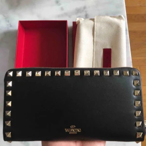  - VALENTINO Rockstud Continental Wallet Calfskinn Black   Äkta och helt oanvänd plånbok från Valentino Garavani. Ord.pris 5580:- Detaljer - bredd 10 cm  - längd 20 cm  - djup 2 cm  100% äkta läder  Made in Italy  Ingår dustbag, äkthetsbevis och box. 