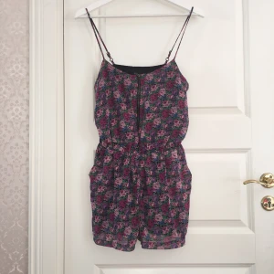  - Fin blommig (lila,rosa,cerise och blå) shortsdress, reglerbar axelband, guldig dragkedja och fickor på sidorna. 