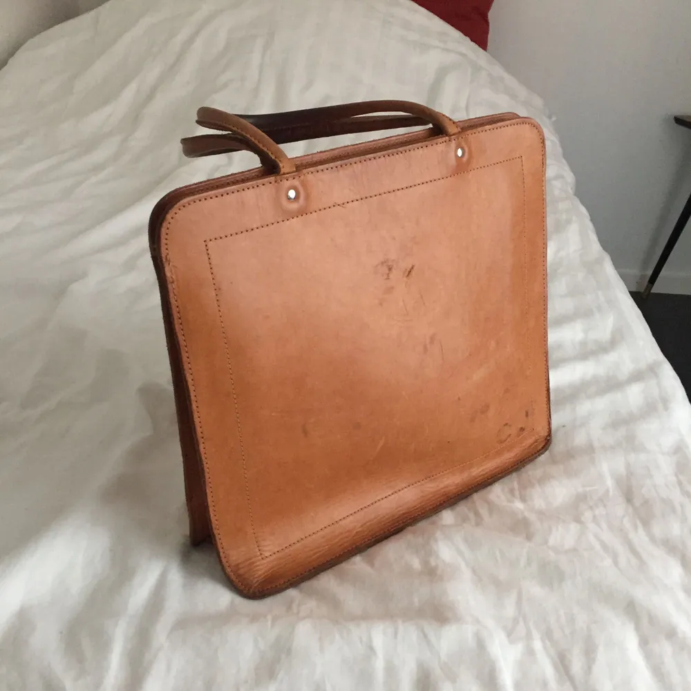 Ljusbrun läderväska från okänt märke.  I använt skick med lite fläckar och en trasig sömm, därav det låga priset.  31 cm bred och 28 cm djup, bara ett stort fack. . Väskor.