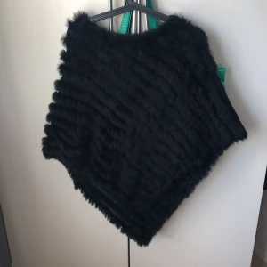 Svart pälsponchoONESIZE - En jättefin svart pälsponcho i storlek onesize köpt från affären Chelsea här i Göteborg. Endast använd fåtal gånger och är som ny. Perfekt att slänga över jackan eller bastoppen nu till hösten.