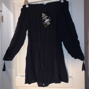 Klänning, strl 34 - Klänning som aldrig har kommit till användning, slapp och skön klänning från Nelly. Är off shoulder och stretchig