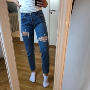 Mom-jeans - Mom-jeans med hål från Brandy Melville i storlek 38 men skulle säga att de passar mer som en 36. Är du intresserad så skriv så kan jag även skicka midje- och längdmått på mig och byxorna. Kan mötas upp i Lund-området eller skickas mot frakt!🥰