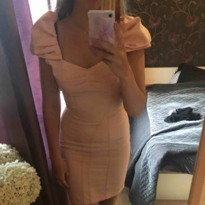 Rosa klänning - Ljusrosa klänning med tight passform. Väldigt fin, själv använt den på ett bröllop & den går även att ”klä ner” med t ex en kofta över. Puffärmarna går att dra ner en aning. Använd 1 gång, nytt skick. Perfekt till sommaren!