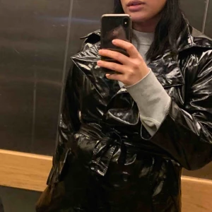  - Tunn lack jacka i svart köpt i second hand. Bältet är lite trasigt.   Frakt tillkommer 